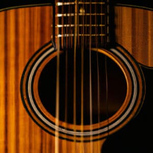 An image capturing the sheer elegance of an Ibanez acoustic guitar, showcasing its lustrous mahogany body, intricate mother-of-pearl inlays, and the delicate curves of its contoured design