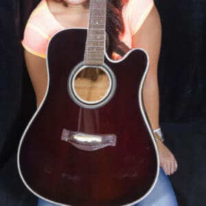 An image showcasing the Taylor 210ce, capturing its elegant sunburst finish on the solid Sitka spruce top, contrasting with the layered rosewood back and sides, while highlighting the exquisite mother-of-pearl inlays on the fretboard